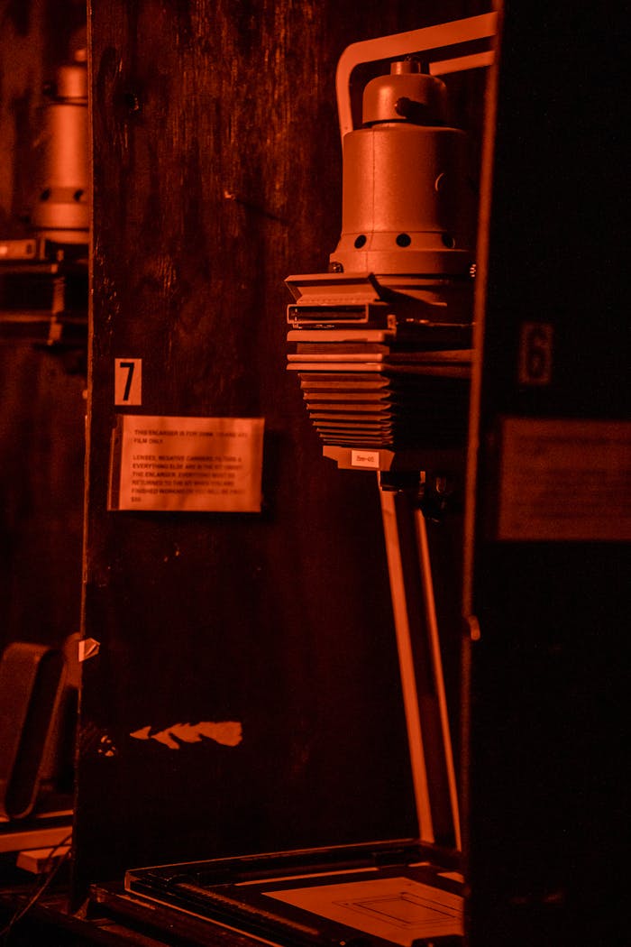 creative-01 A vintage darkroom enlarger lit by red light used for developing photographs.
