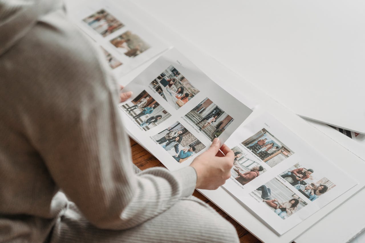 digital Individual in casual attire reviewing printed photo sheets indoors, capturing nostalgic moments.