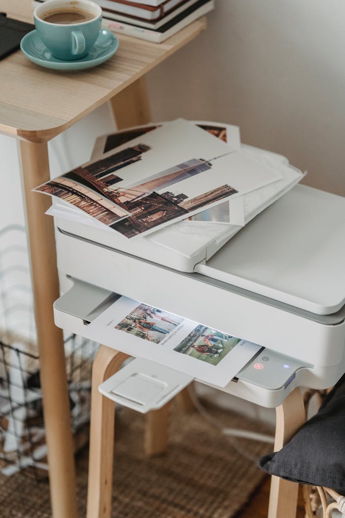digital-01 A cozy home office corner with a printer, coffee cup, and printed photos on a wooden table.