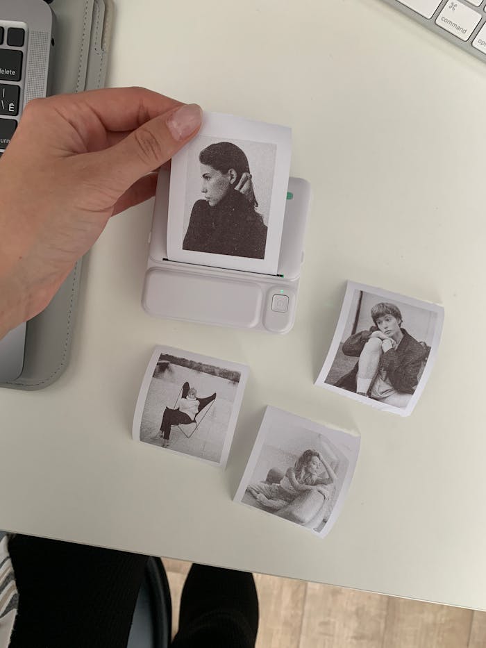 Services-01 A hand using an instant photo printer to create black and white portraits on a desk.